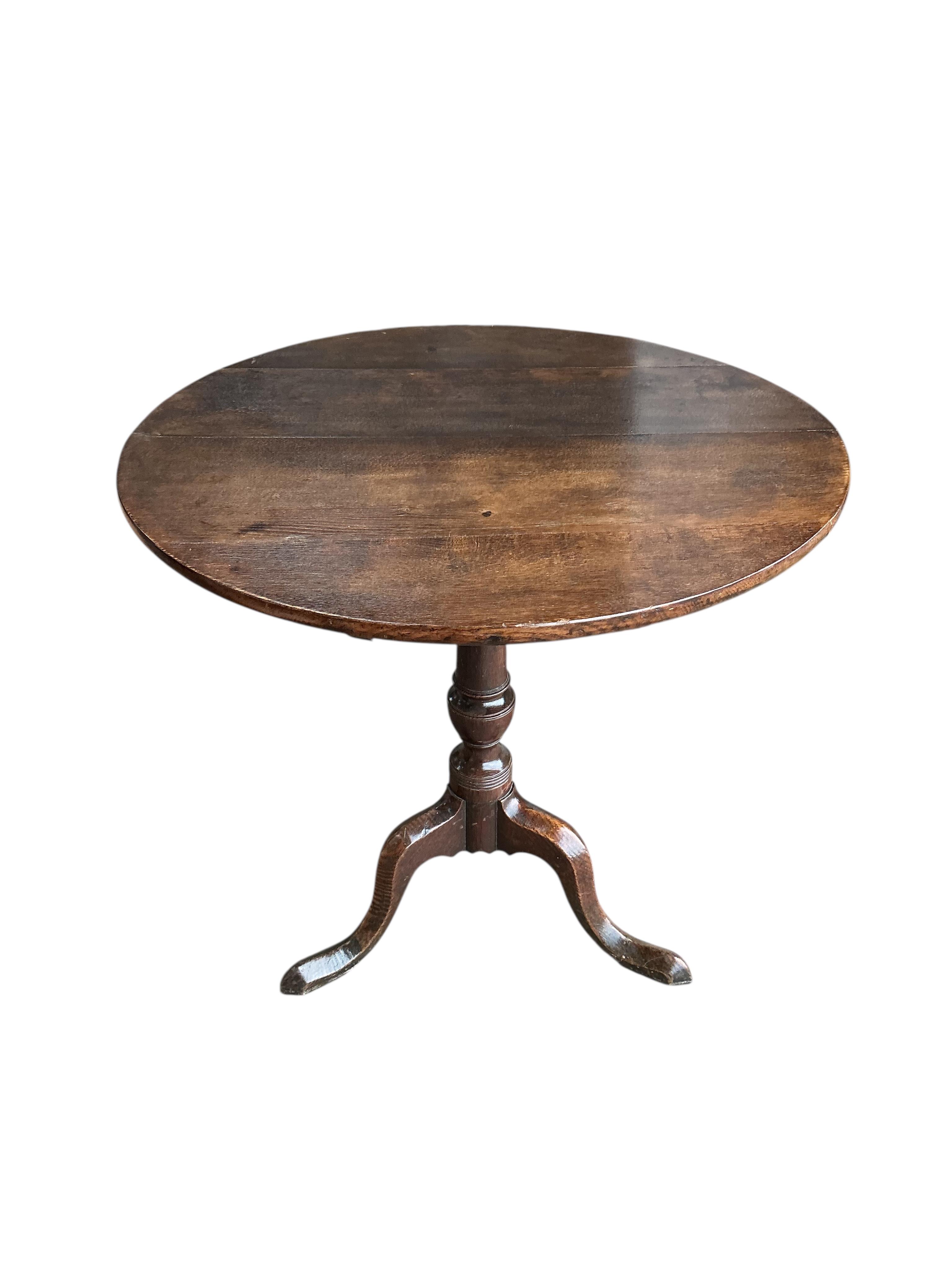An early 19th century circular oak tilt top tripod tea table, diameter 76cm, height 72cm